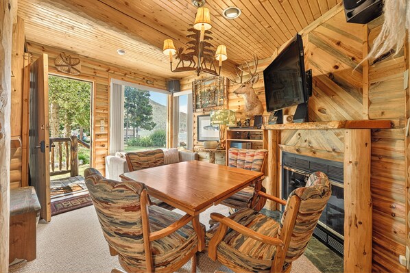 Un interior de madera con una mesa de comedor y sillas, una chimenea y un televisor montado en la pared.
