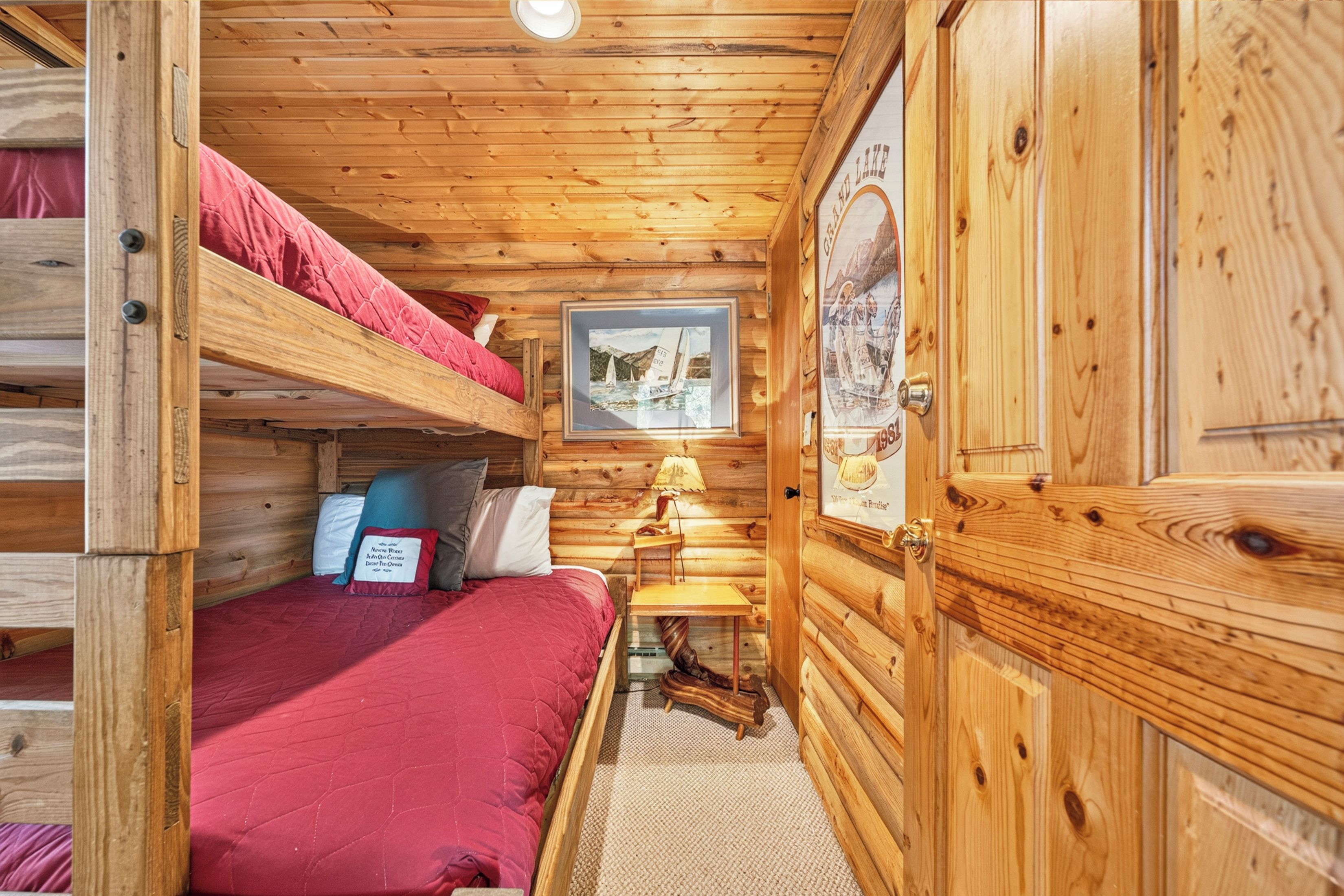 Ein Blockhauskamin mit Etagenbett, einem kleinen Tisch mit Lampe und einem gerahmten Bild an der Wand.