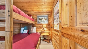 Ein Blockhauskamin mit Etagenbett, einem kleinen Tisch mit Lampe und einem gerahmten Bild an der Wand.