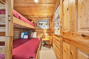 L'intérieur d'une cabine avec un lit superposé, une petite table avec une lampe et un tableau encadré au mur.