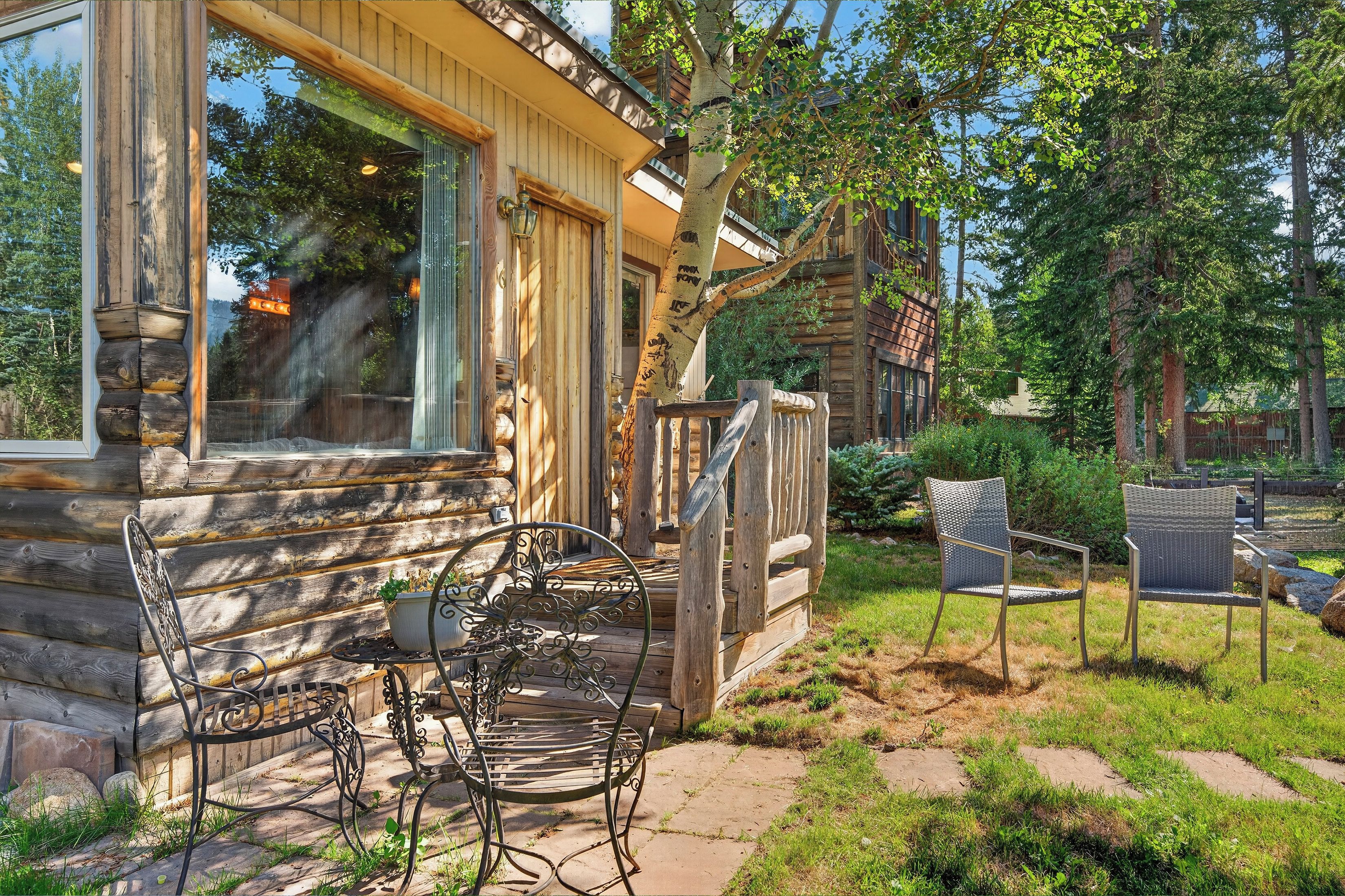 Eine Blockhütte mit Veranda, Sitzgelegenheiten im Freien und Blick auf den umliegenden Wald.
