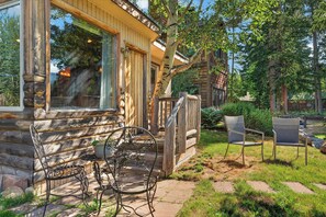 Eine Blockhütte mit Veranda, Sitzgelegenheiten im Freien und Blick auf den umliegenden Wald.