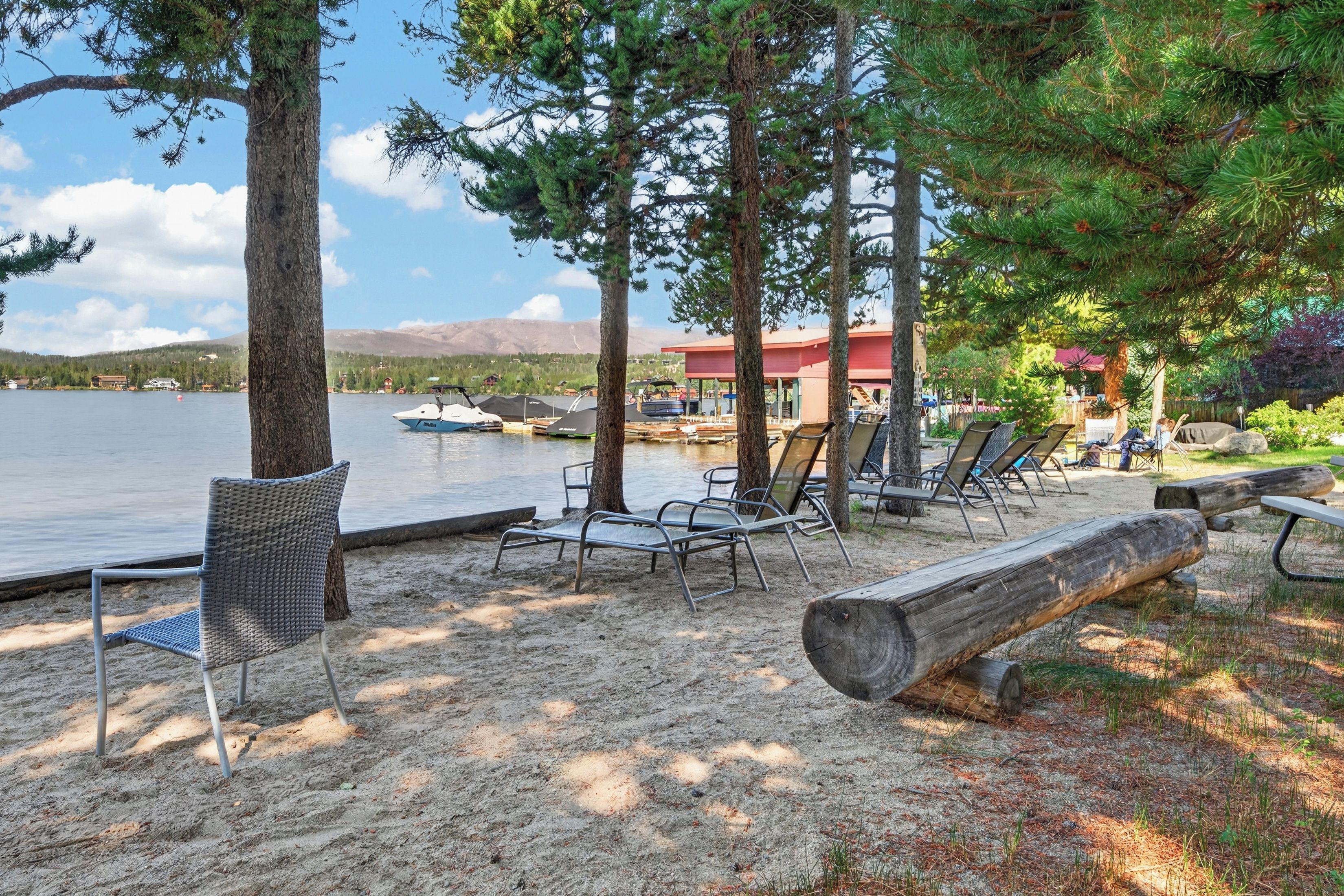 A lakeside resort with lounge chairs and a dock with boats.