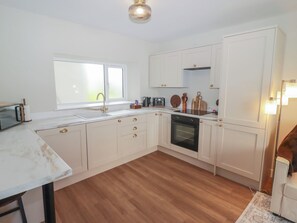 A modern kitchen with white cabinetry, a built-in oven, and a window.