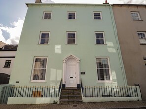 A two-story building with a central entrance, a small porch, and a sign indicating 'DOLPHIN HOUSE.'