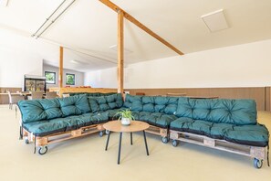 Ein großes, modulares Sofa auf Rollen, ein kleiner runder Tisch und ein Blumentopf in einem modernen Innenraum.