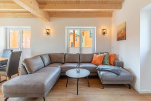 Ein modernes Wohnzimmer mit einem Ecksofa, einem runden Couchtisch und zwei Wandleuchten.