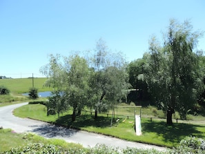 Uma estrada rural serpenteando por uma paisagem verde com árvores e céu claro.