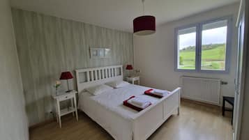A bedroom with a bed, bedside tables, a window with a view, and a radiator.