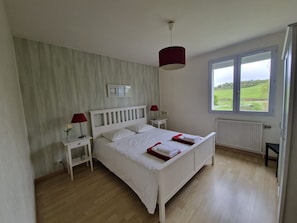 Quarto com cama, mesas de cabeceira, janela com vista e radiador.