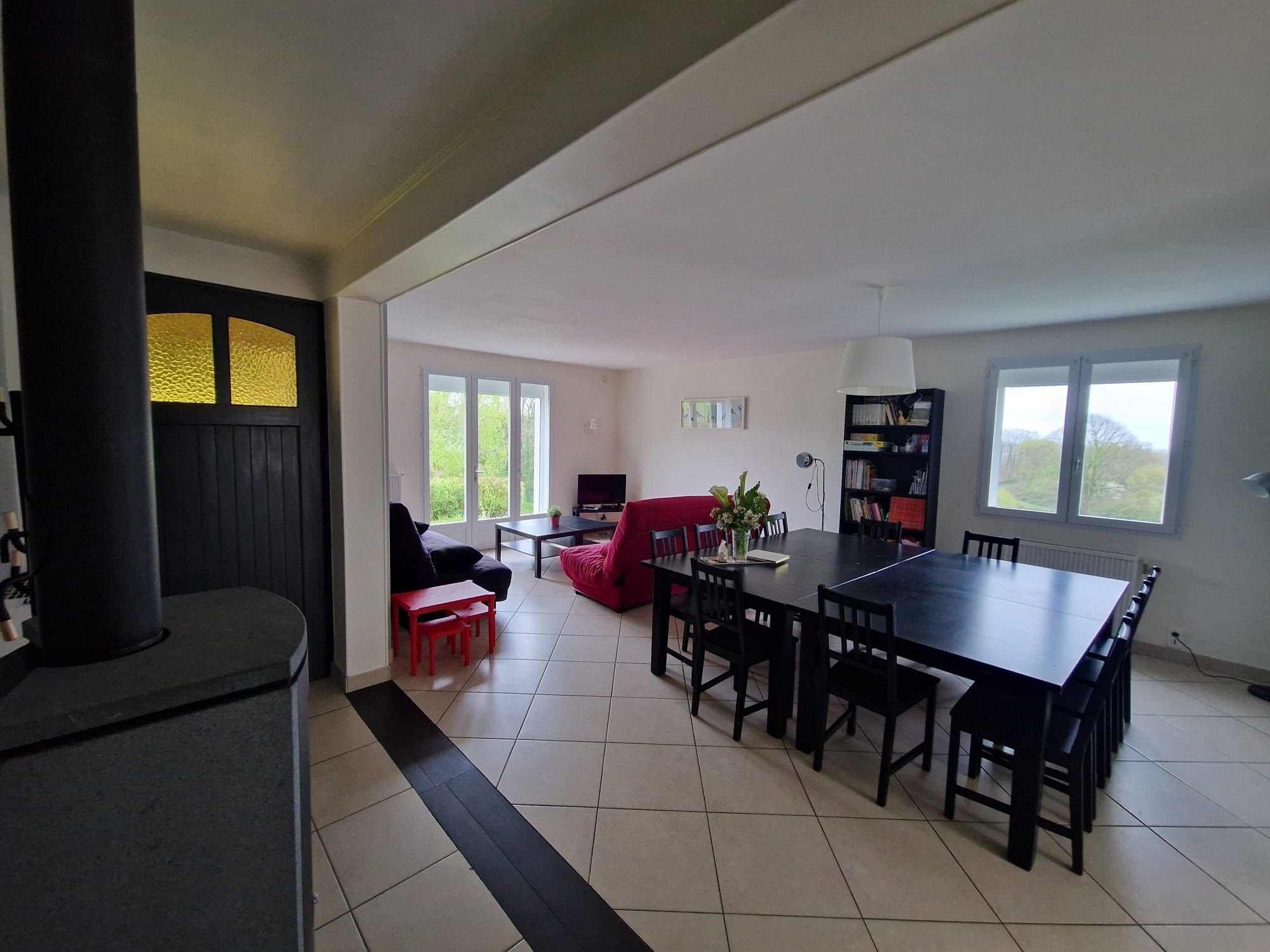 A spacious living area with a fireplace, a dining table, and a red sofa.
