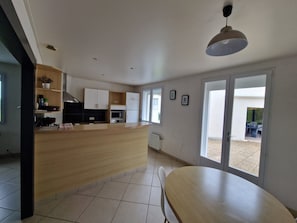 Cozinha moderna com ilha central, mesa de jantar e vista pelas portas de vidro.