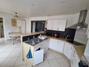 A modern kitchen with a central island, white cabinetry, and a stainless steel sink.