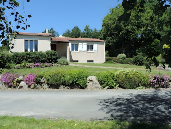 Uma casa de dois andares com um jardim na frente.