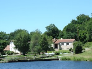 A lakeside property with a house, a dock, and lush greenery.