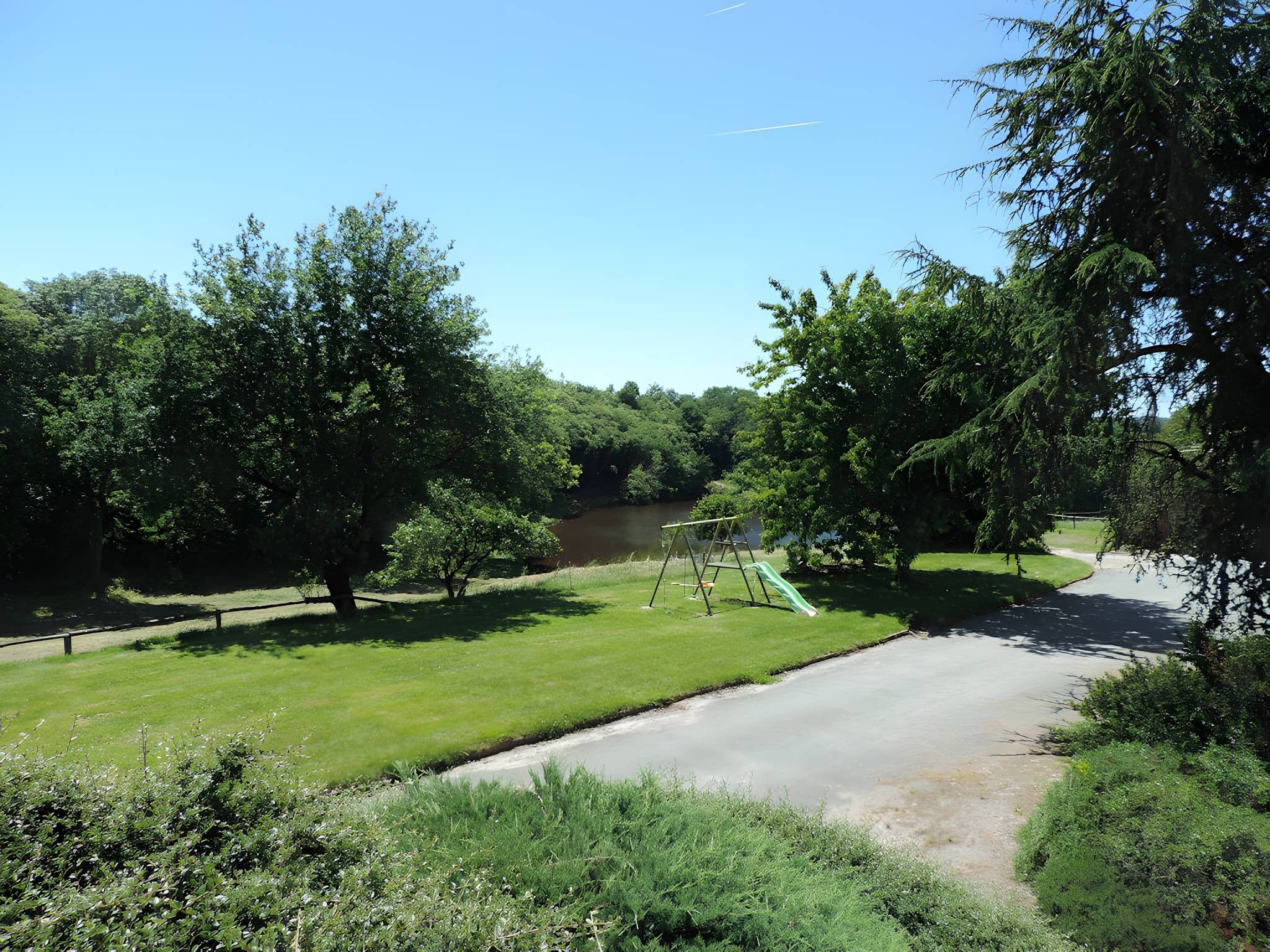 Un parc doté d’une aire de jeux, d’un chemin pavé et d’un plan d’eau.