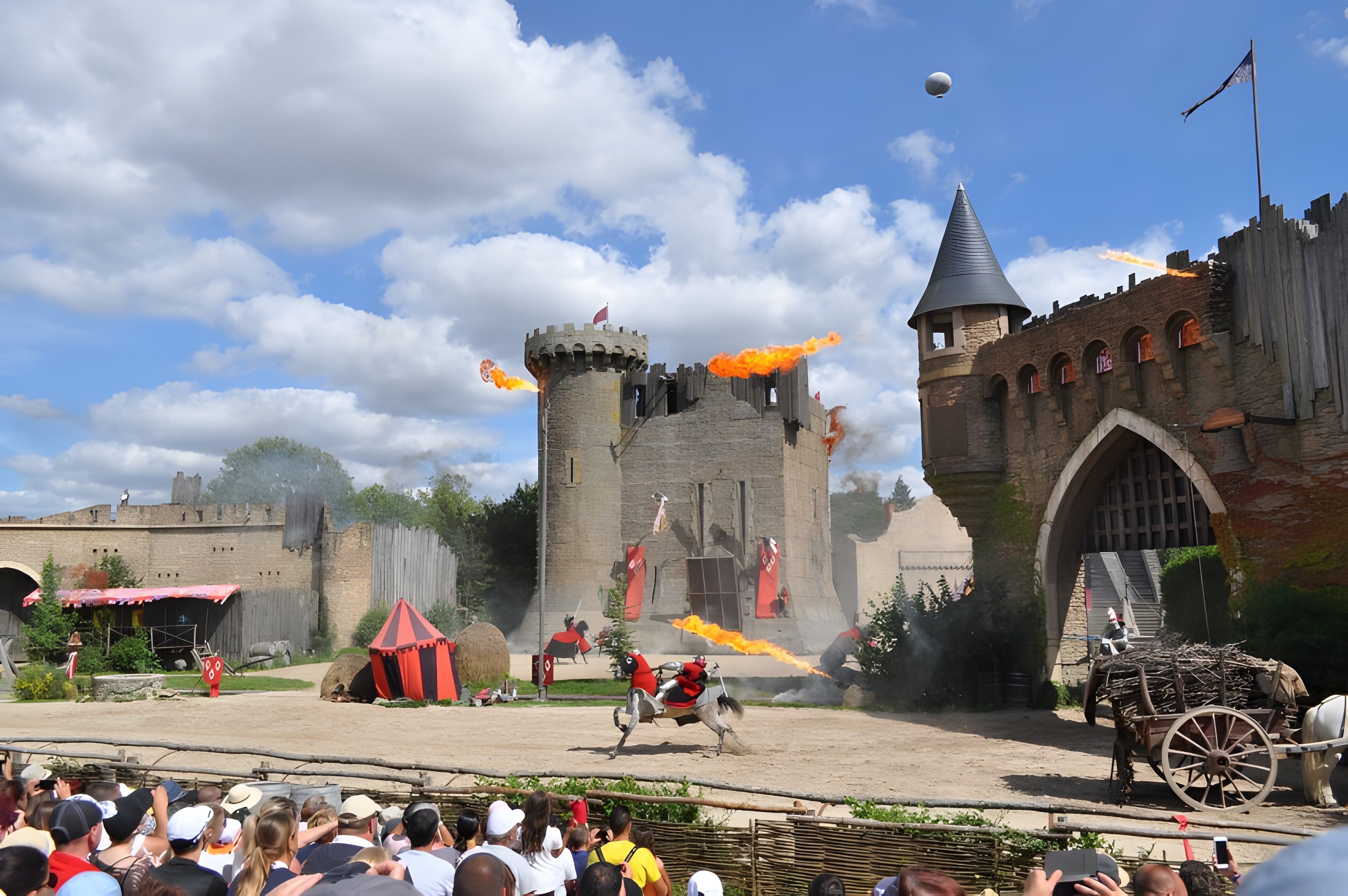 A medieval-themed event with a castle backdrop, performers in costumes, and a crowd watching.