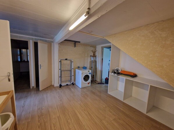 A laundry room with a washing machine, drying rack, and shelves.