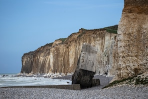 A coastal cliff with a large rock formation and a pebble beach. - Holiday Home 'Maisonnette De Sotteville Sur Mer' with Private Terrace, Private Garden and Wi-Fi (Sotteville-sur-Mer)