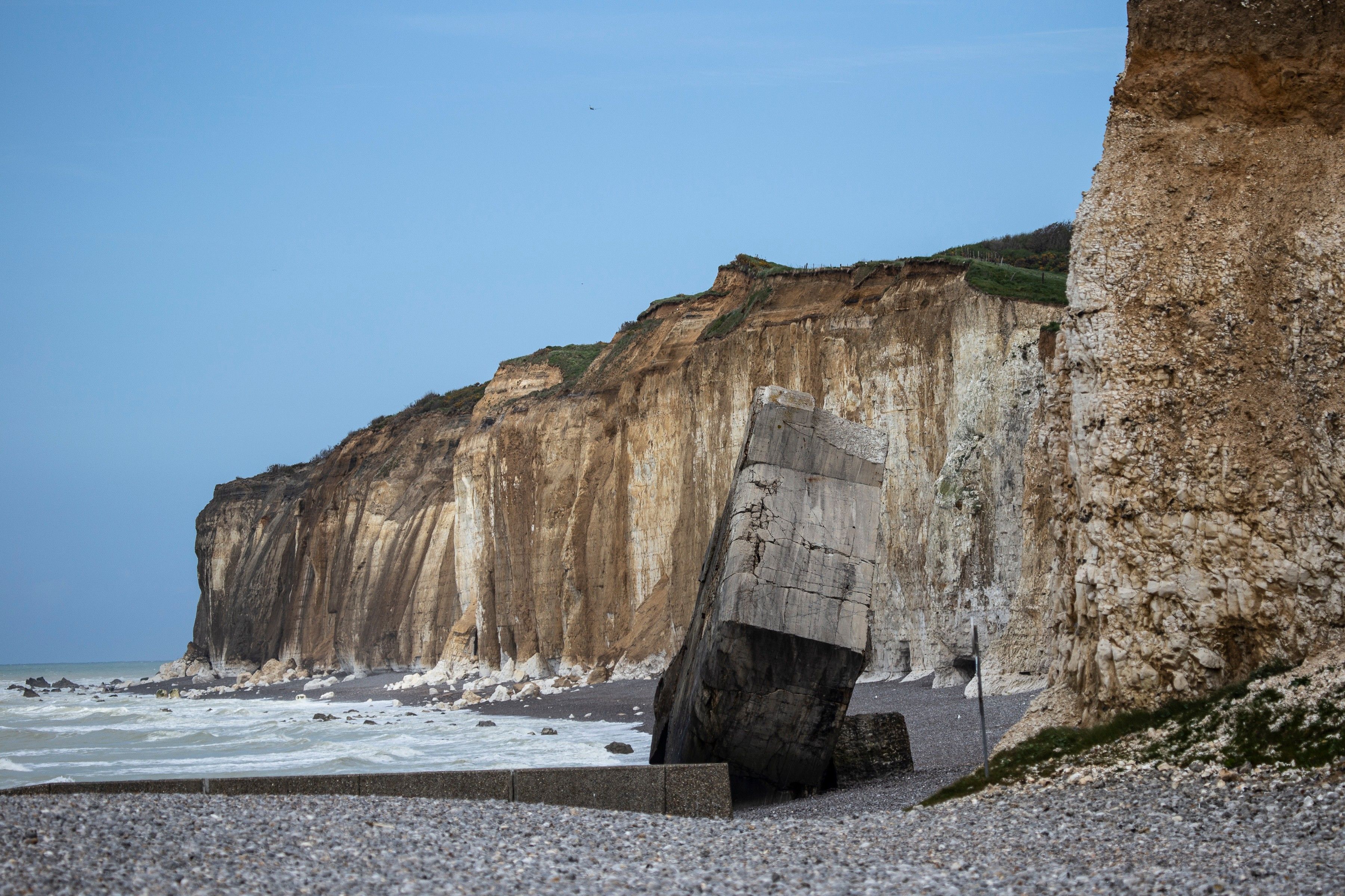 Eine Küstenklippe mit einer großen Felsformation und einem Kiesstrand.