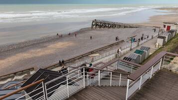 Ein Strand mit einer Holzsteganlage, einem Felsweg und einer Aussichtsplattform mit Geländern.