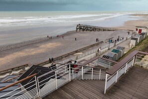 Ein Strand mit einer Holzsteganlage, einem Felsweg und einer Aussichtsplattform mit Geländern.