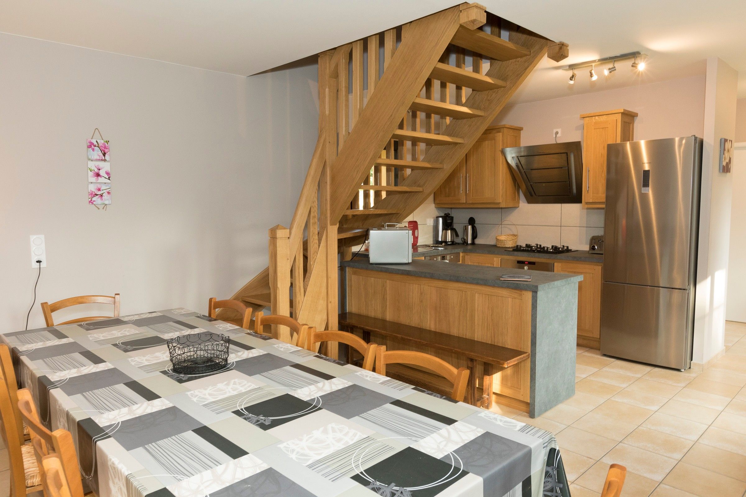 Eine moderne Küche mit Einbauherd, einem Edelstahlkühlschrank und Holzschränken.