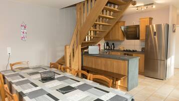 Eine moderne Küche mit Einbauherd, einem Edelstahlkühlschrank und Holzschränken.