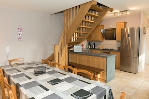 A modern kitchen with a built-in stove, a stainless steel refrigerator, and wooden cabinets.