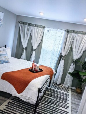 A neatly made bed with a tray of items, a black metal bed frame, a striped rug, and a potted plant. - Peaceful 2-bedroom, 2-bathroom Luxury with AC, Elevator in vibrant Philadelphia (Philadelphia)