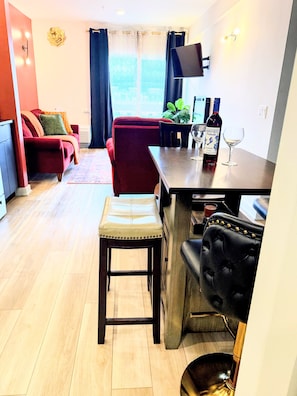 A modern living room with a red sofa, a wooden dining table, and a kitchen area with a bar stool. - Peaceful 2-bedroom, 2-bathroom Luxury with AC, Elevator in vibrant Philadelphia (Philadelphia)