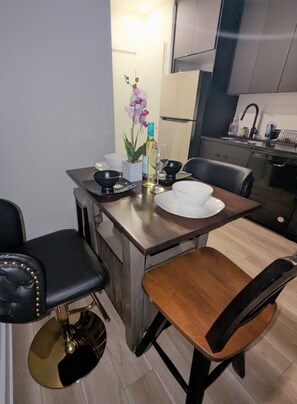A compact kitchen with modern appliances, a dining table with chairs, and a small potted orchid. - Peaceful 2-bedroom, 2-bathroom Luxury with AC, Elevator in vibrant Philadelphia (Philadelphia)
