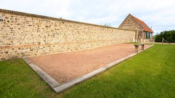 Ein Innenhof mit Steinmauer, Kiesfläche und einem Gebäude mit rotem Dach.