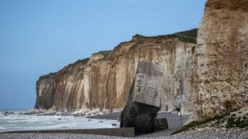 Eine Küstenklippe mit einer großen Felsformation und einem Kiesstrand.