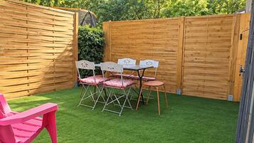 A backyard with a patio area, a table with chairs, and a pink chair.