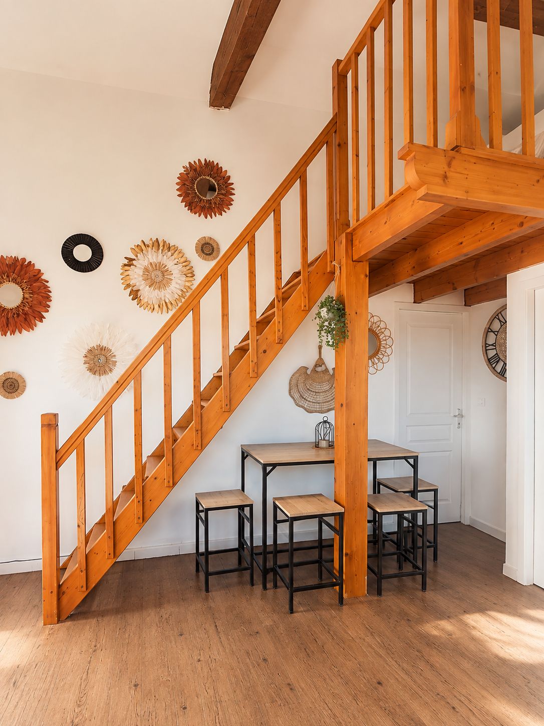 Un escalier en bois mène à un espace repas comprenant une table et des chaises.