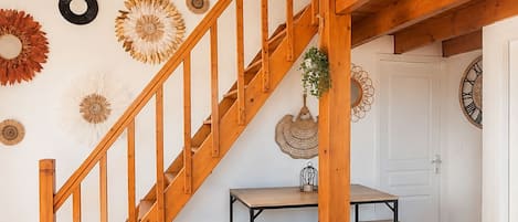 A wooden staircase leading to a dining area with a table and chairs.