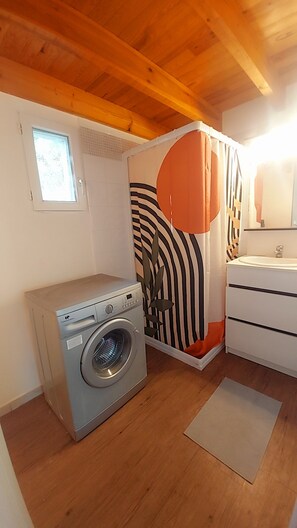 A compact room with a washing machine, a sink, and a window.