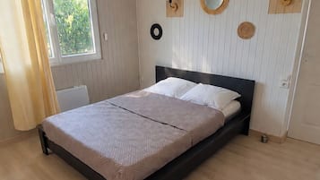 A bedroom with a bed, a window with curtains, and wall-mounted decor.