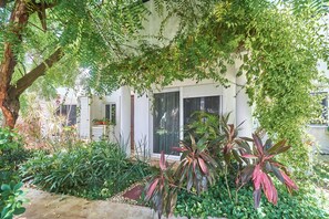 A building with a white exterior, surrounded by lush greenery and various plants. - Quiet 3BR townhouse in gated Playacar (Playa del Carmen)