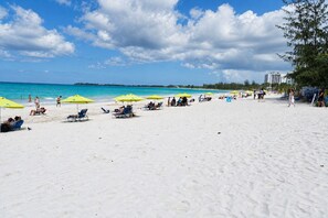A beach with white sand, yellow umbrellas, and people relaxing. - Solara Pine & Tide — Beach Studio in Isla Verde <br>Welcome to Solara Pine & Tide, a cozy and efficient 215 sq ft beach apartment located in Condominium Dalia 15 on Dalia Street — right in the heart of Isla Verde. (Carolina)