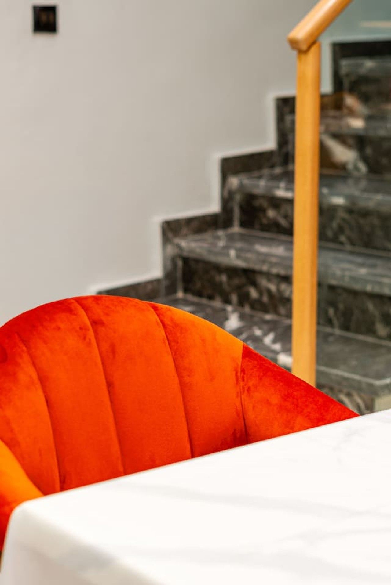 Un coin repas avec une table blanche et une seule chaise orange.