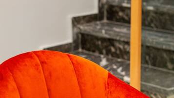 Un coin repas avec une table blanche et une seule chaise orange.