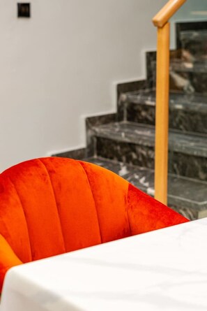 Un coin repas avec une table blanche et une seule chaise orange.
