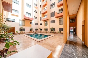Un bâtiment moderne doté d’une piscine centrale, de nombreux balcons et d’un sol carrelé et impeccable.