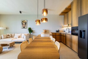 Eine moderne Küche mit Holzausstattung, einem Edelstahlkühlschrank und einer Essecke mit Holztisch und Korbstühlen.