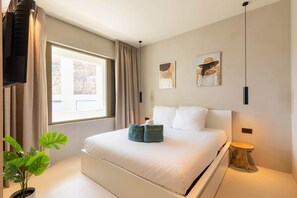 Een moderne slaapkamer met een groot bed, een raam met gordijnen, een potplant en kunst aan de muren.