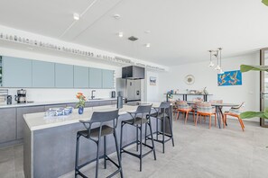 Eine moderne Küche mit einer zentralen Kochinsel, Barhocker und einem Essbereich mit Tisch und Stühlen.