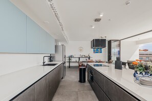 A modern kitchen with a central island, a dining area with a view, and a small seating space. - NEW Harbour Nine at The Wharf Urban Elegance (Willemstad)