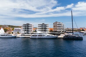 A marina with several yachts docked, modern buildings in the background, and a clear sky. - NEW Harbour Nine at The Wharf Urban Elegance (Willemstad)